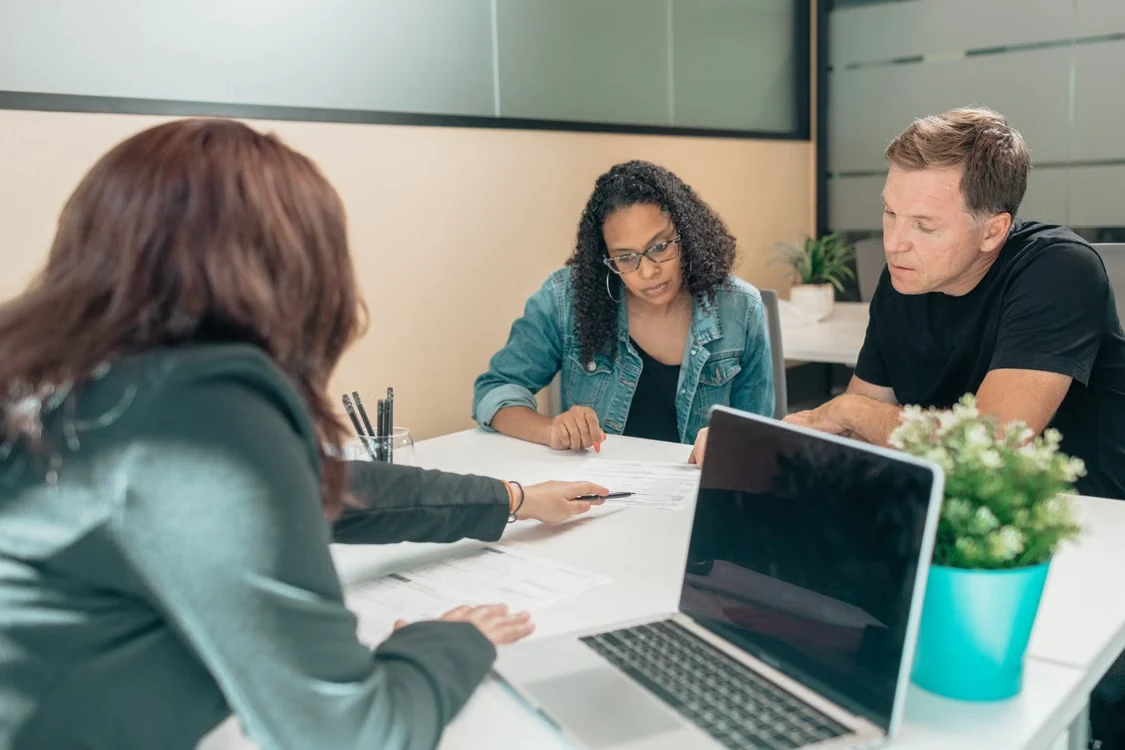 A couple reviewing documents with a professional in an office setting, focusing on estate planning