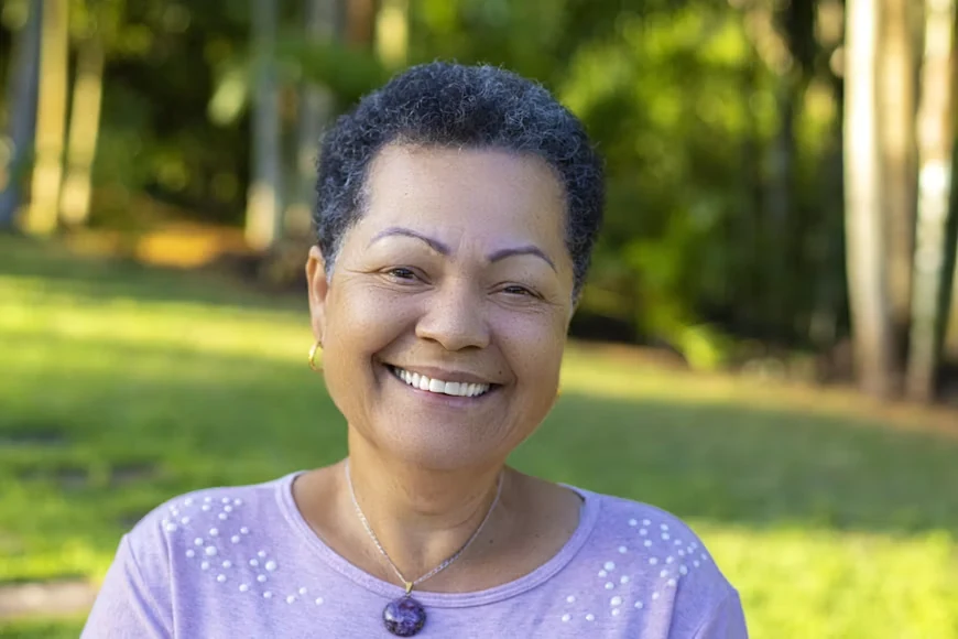 An older woman in a purple shirt smiling