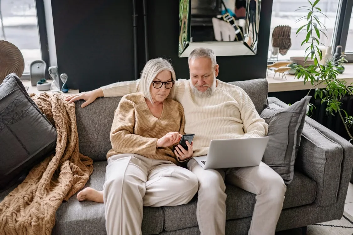 Senior couple sitting on their couch looking through finances.