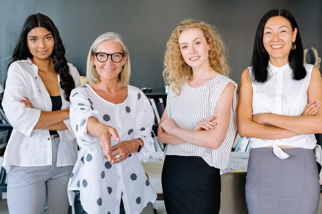 Smiling group of women, arms crossed, in modern office setting