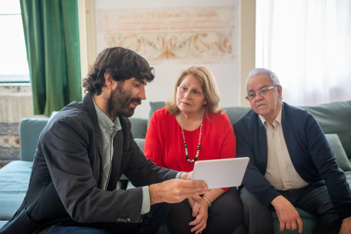 An advisor discussing financial documents with a senior couple in a cozy living room