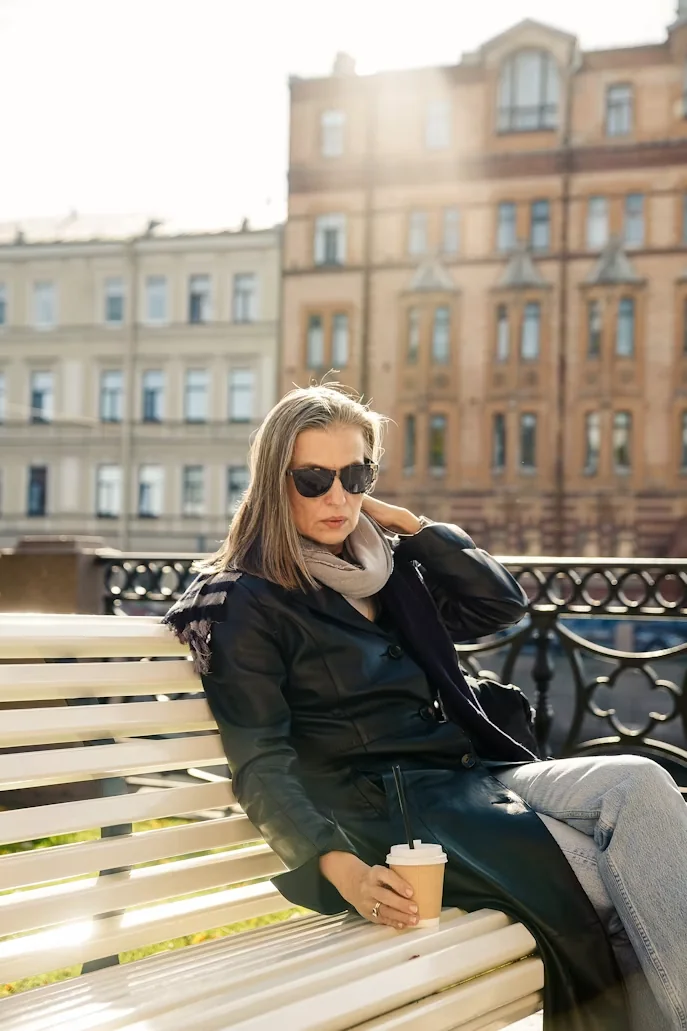 A middle-aged woman sitting outside on a bench