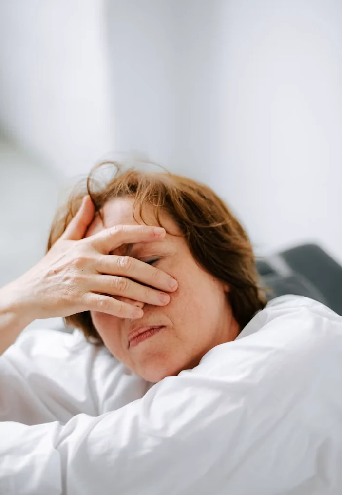 A sad woman sitting on a couch with her hands on her head
