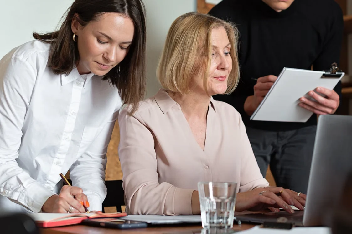 Three colleagues collaborating in a well-lit office space, focused on financial planning tasks.
