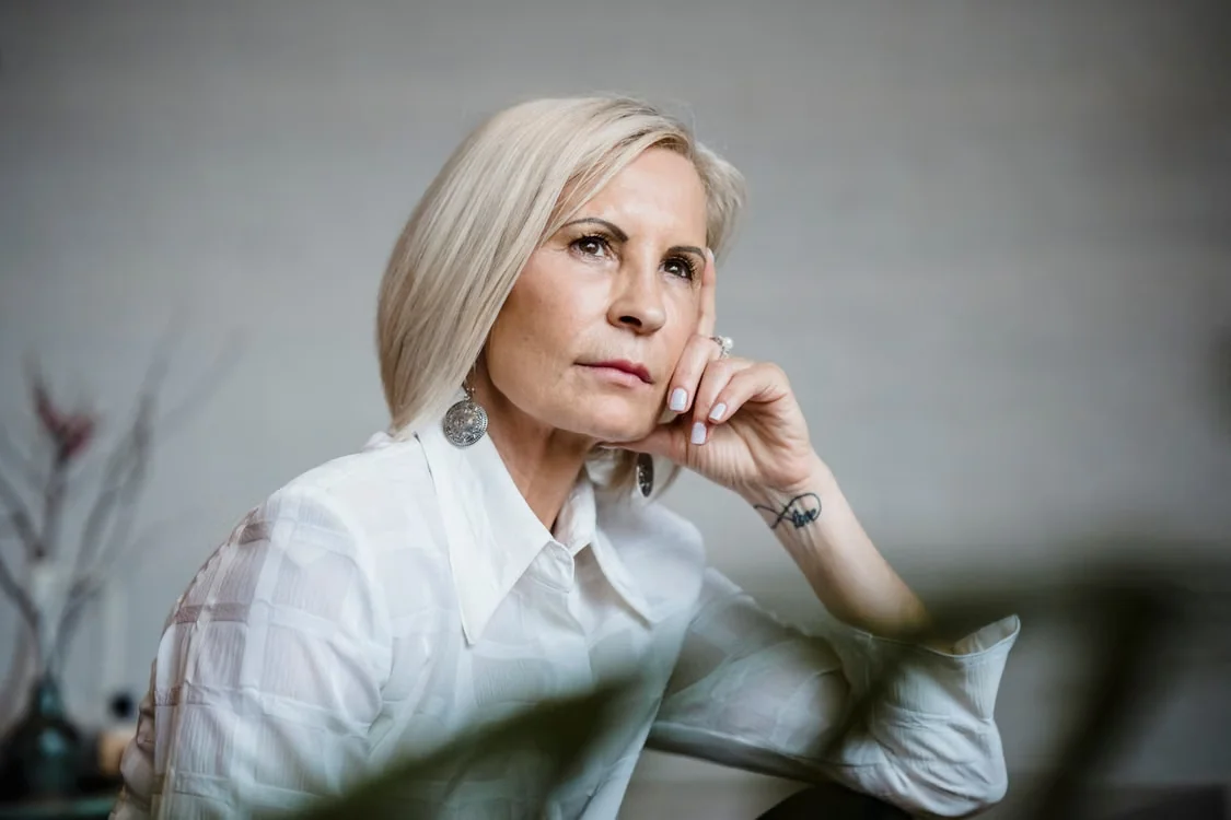 Senior woman lost in pensive thought indoors.