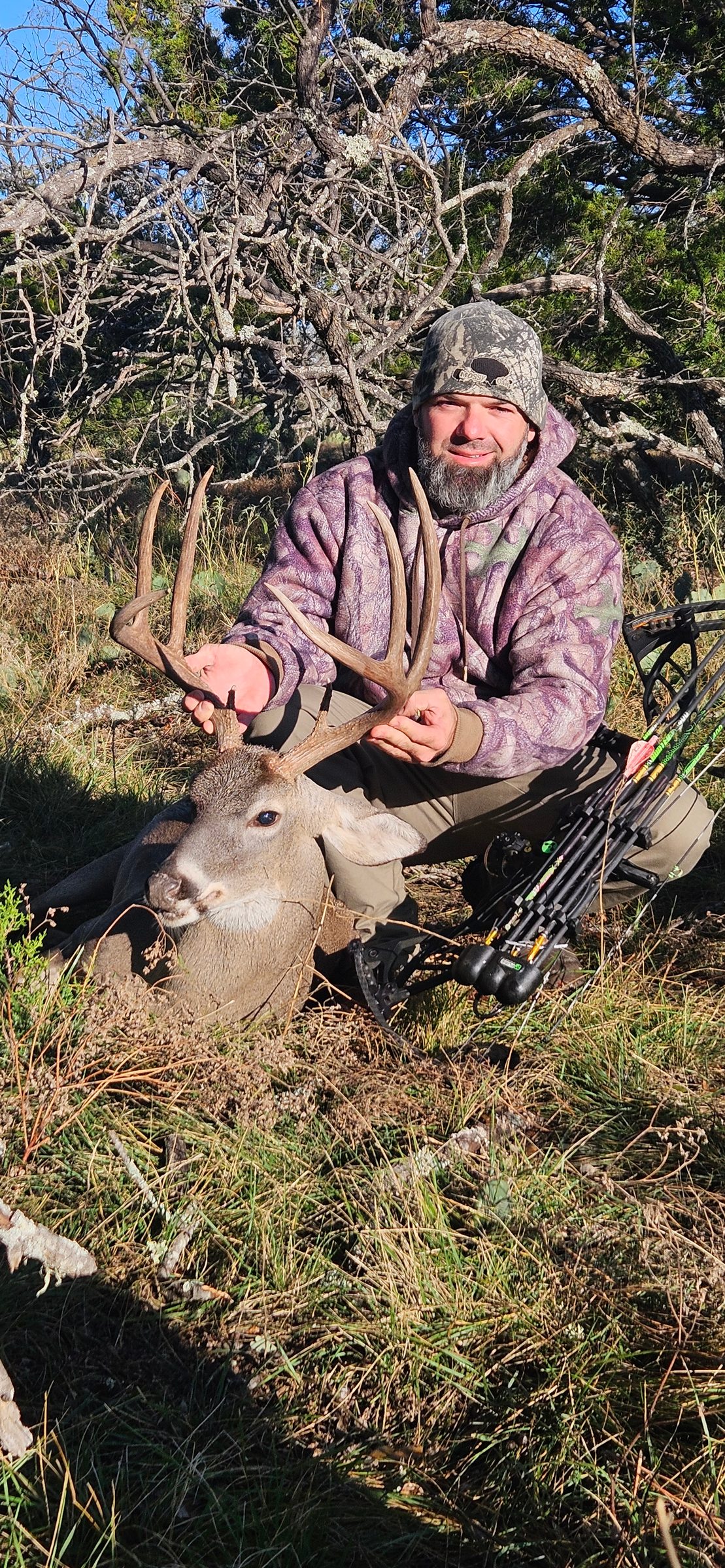 Bow hunter with a harvested whitetail buck in cedar cover at FF Hunting Ranch