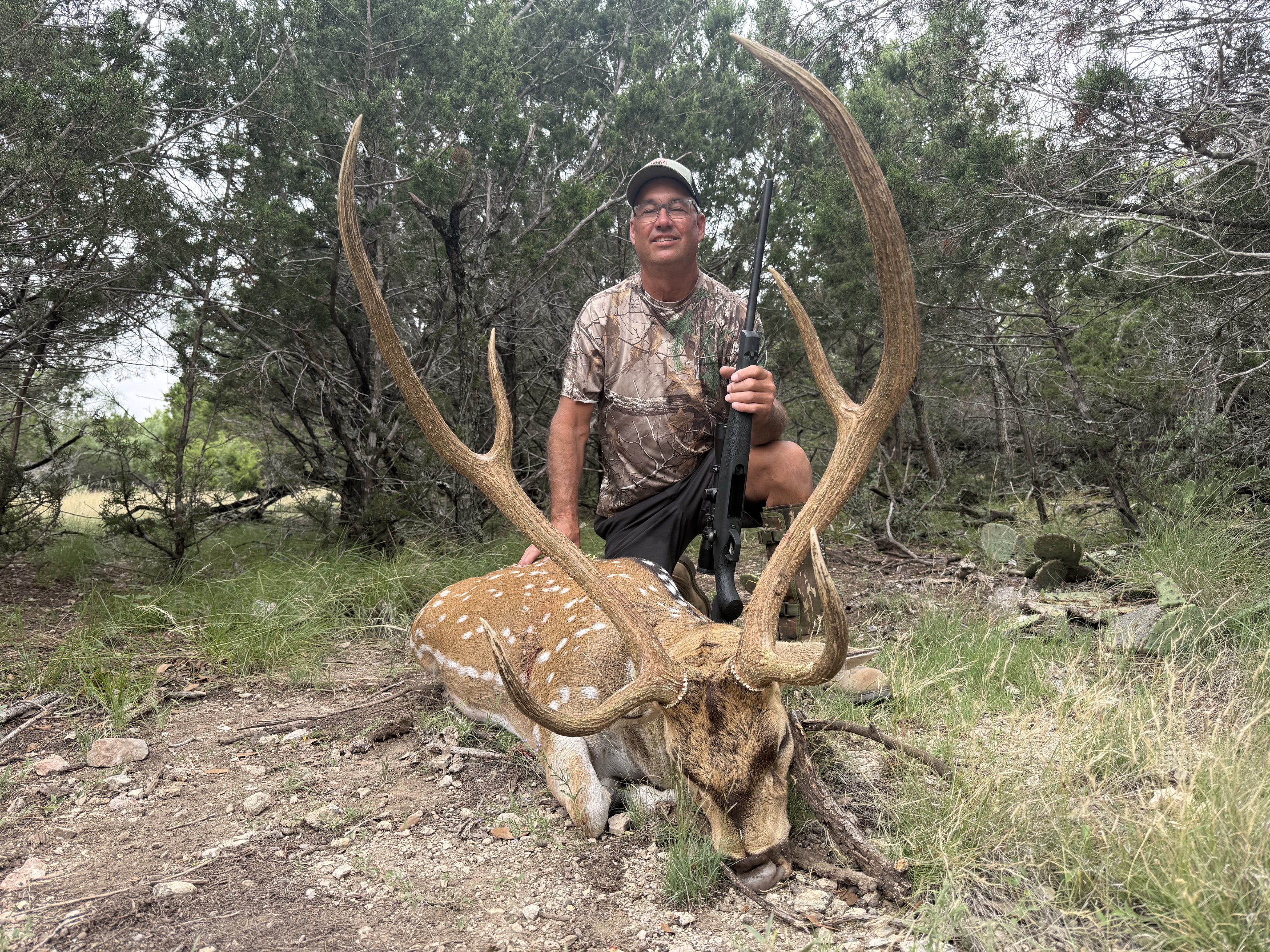 Axis hunter with a mature buck in cedar country at FF Hunting Ranch